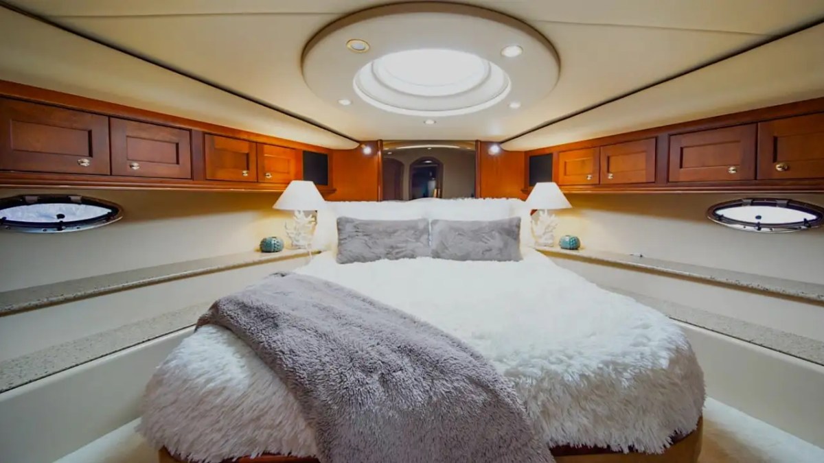 Luxurious yacht bedroom with a large bed, wood cabinets, and round ceiling light.