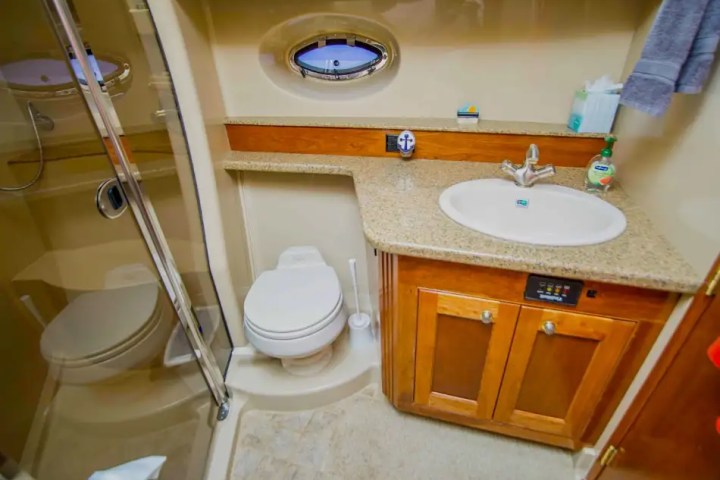 Compact bathroom with a shower, toilet, sink, and wooden cabinet.