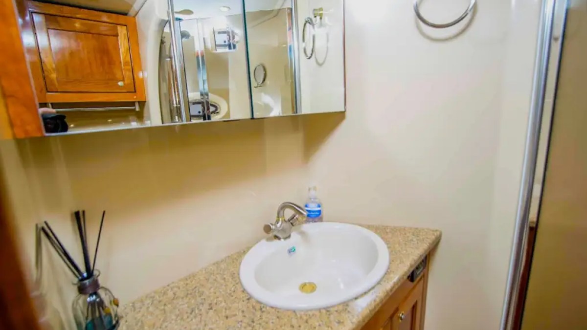 Bathroom with mirror, sink on granite counter, cabinet, and a towel ring on wall.