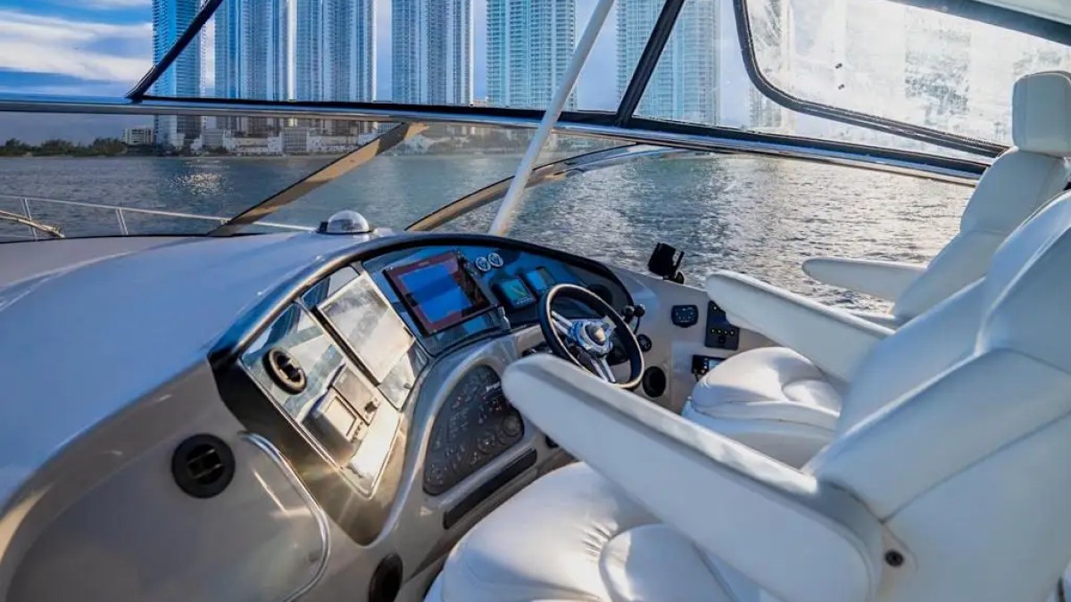 Yacht cockpit with two white seats and city skyline in the background.