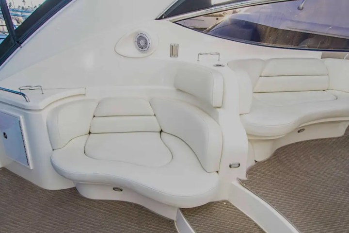 Luxurious boat seating area with white cushioned seats and carpeted flooring.