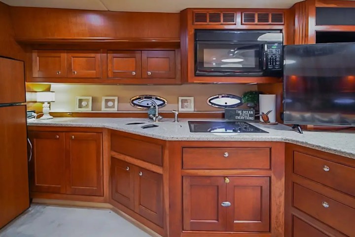 Wood-paneled yacht kitchen with microwave, TV, and countertops.