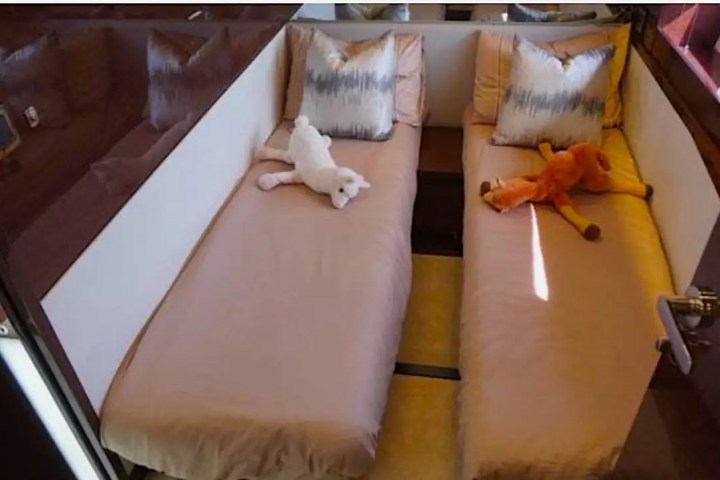 Two beds in a small room with plush toys and patterned pillows.