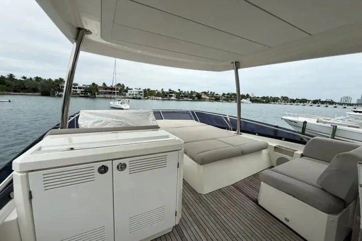 Upper deck of a yacht with seating, a cabinet, and ocean view.