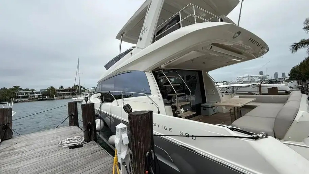 Luxury yacht docked at a marina with a cloudy sky overhead.