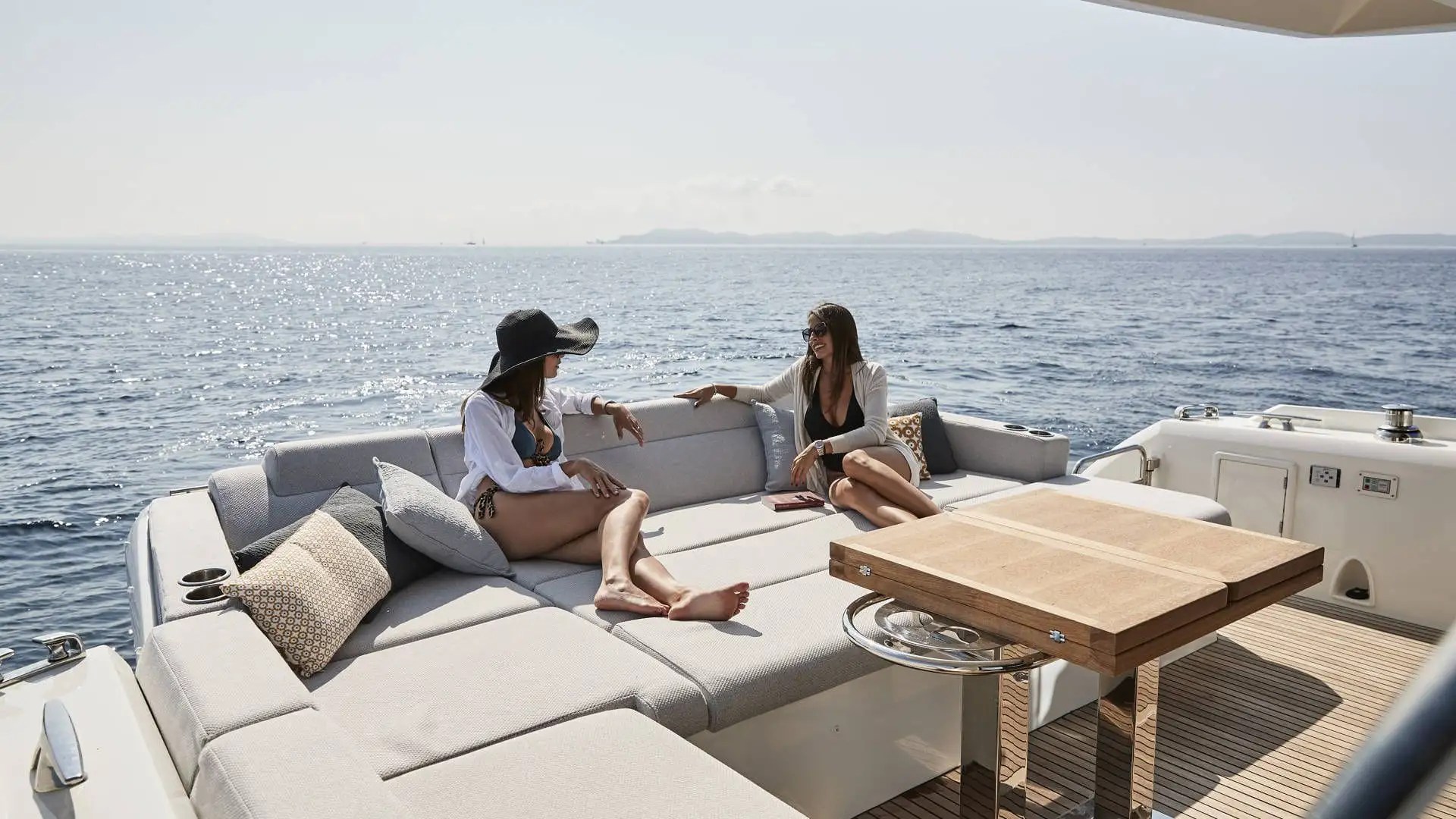 Two guests sitting on the aft deck of a 60′ Prestige yacht in Miami Beach