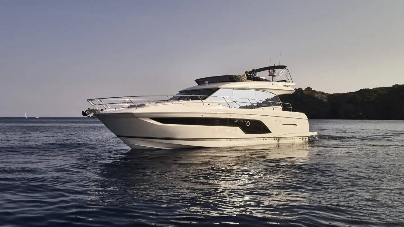 A luxury motor yacht on calm waters with an island in the background.