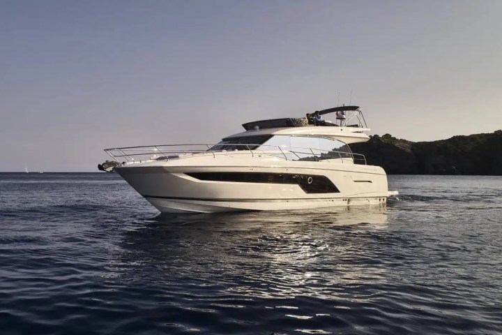 A luxury motor yacht on calm waters with an island in the background.