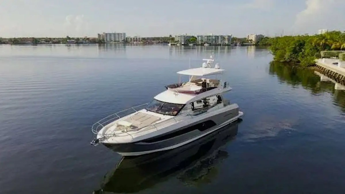 Luxury yacht on calm water with urban skyline in the background.