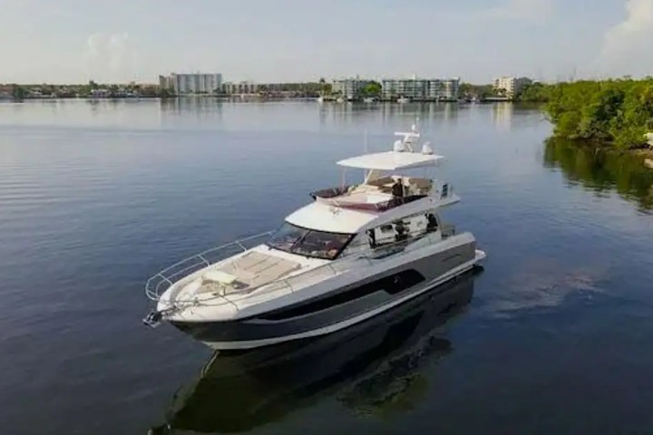 Luxury yacht on calm water with urban skyline in the background.