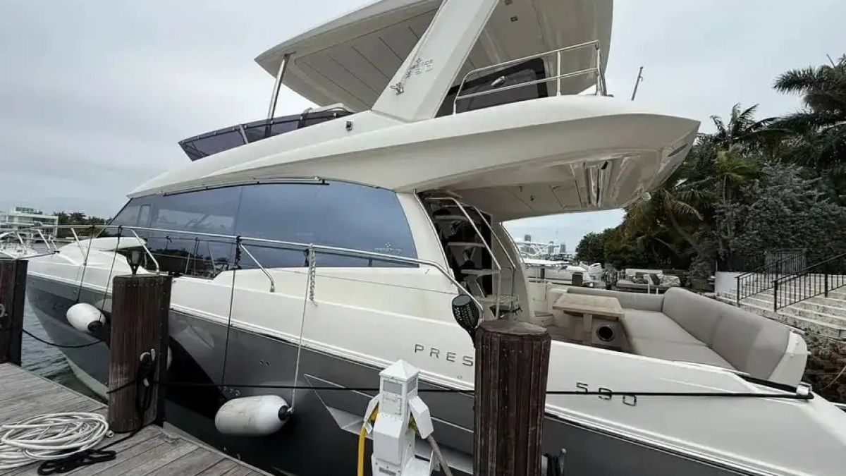 Luxury yacht docked at harbor with flybridge and sleek design.