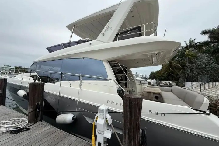 Luxury yacht docked at harbor with flybridge and sleek design.