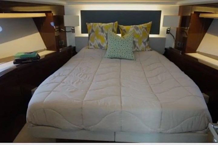 Cozy bedroom with a double bed, colorful pillows, side tables, and ambient lighting.