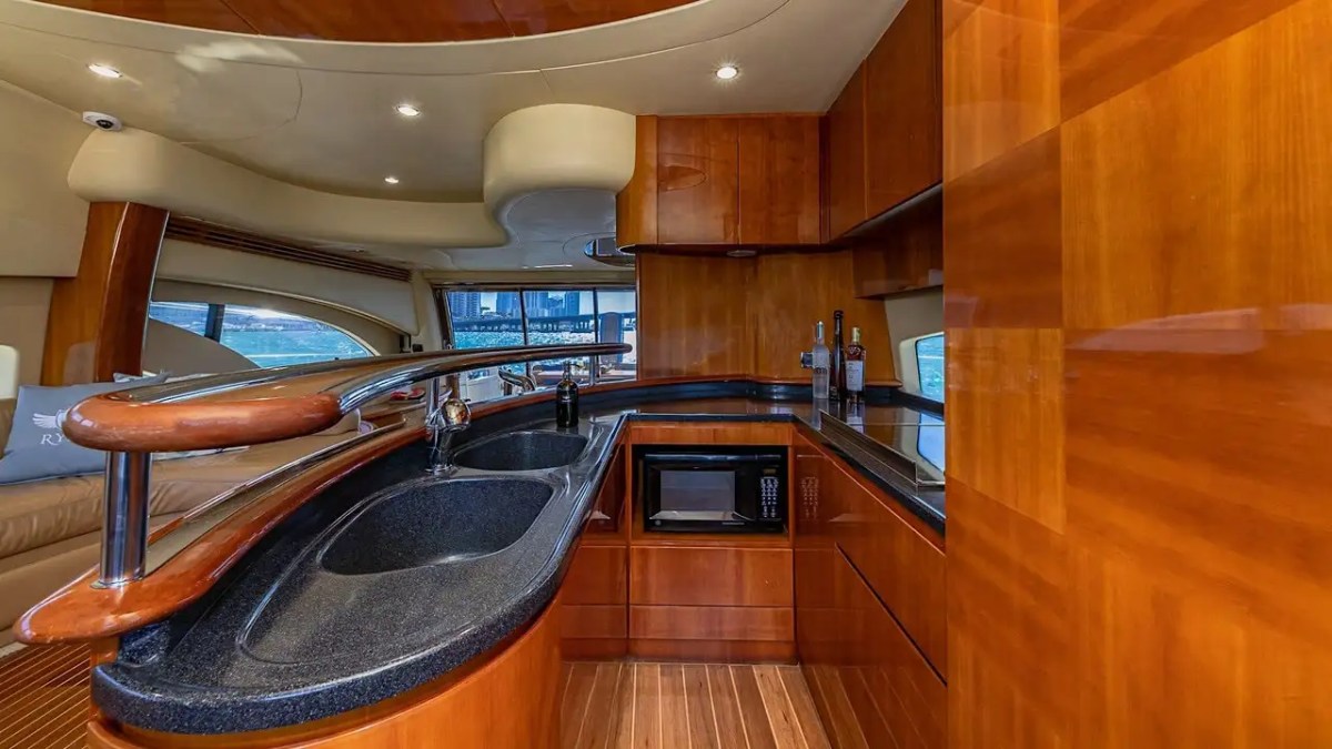 Luxurious yacht kitchen with wood finish, black countertops, and large windows.