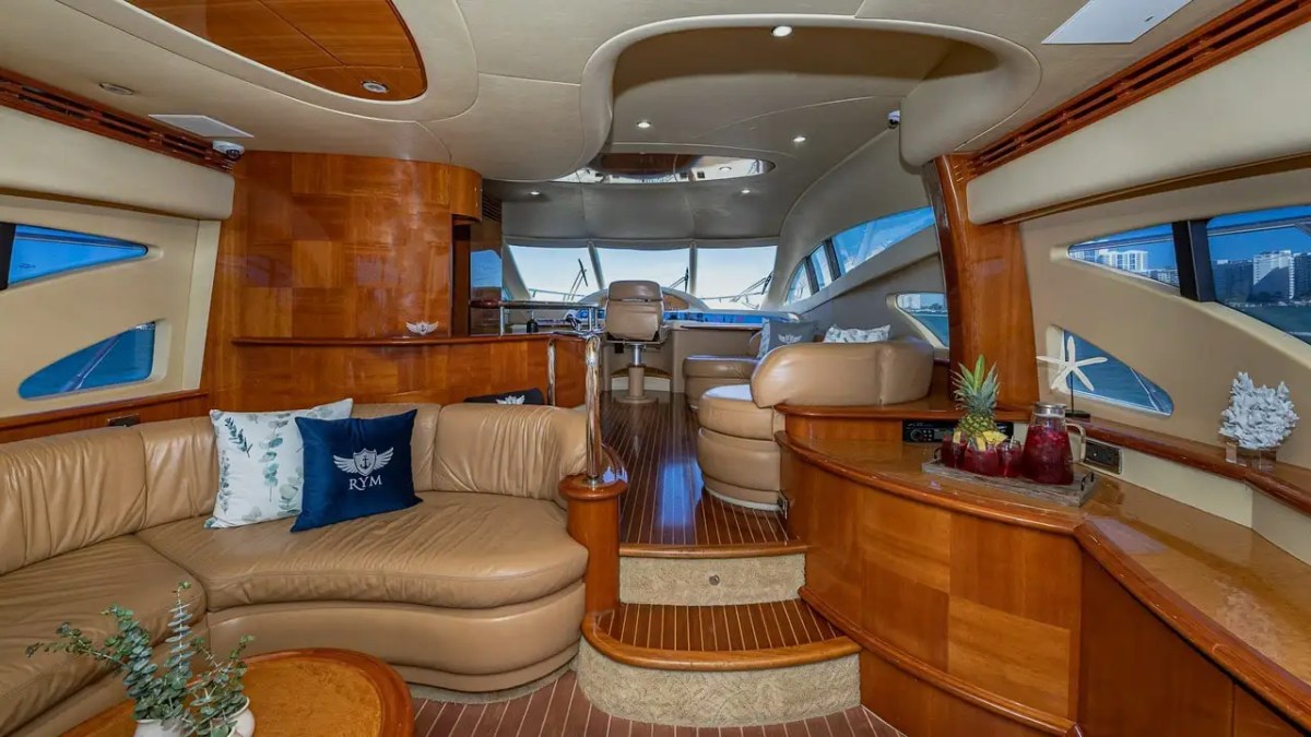 Luxurious yacht interior with leather seating, wooden accents, and large windows overlooking the water.