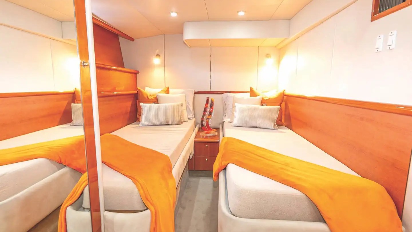 A cozy cabin with two single beds, orange throws, and soft lighting.