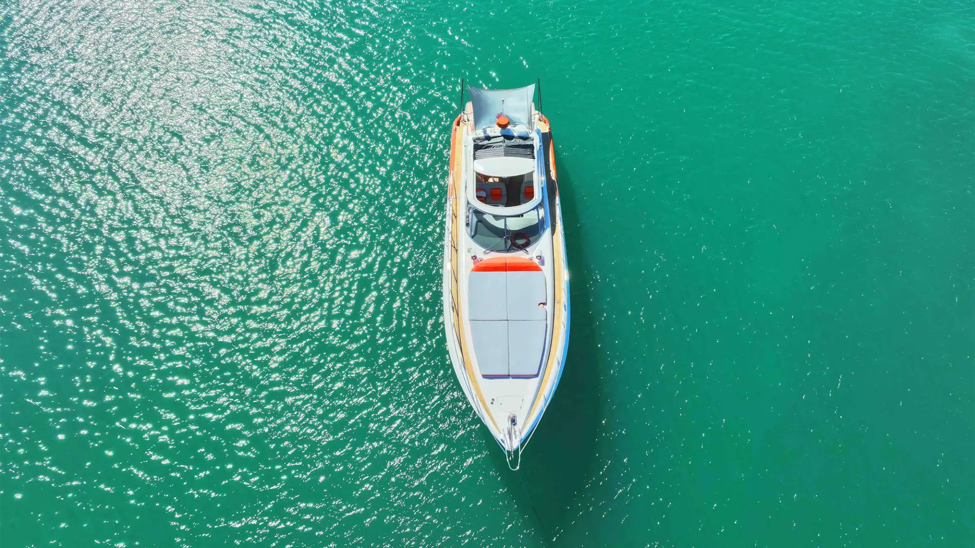 Top view of a white boat on clear turquoise water.