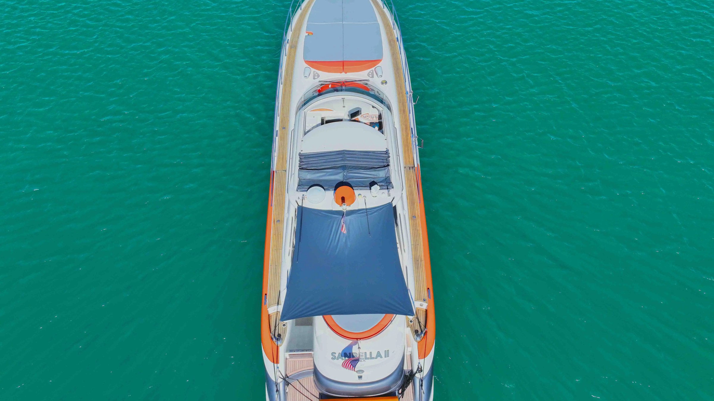 Aerial view of a luxury yacht with sunshade on blue water.