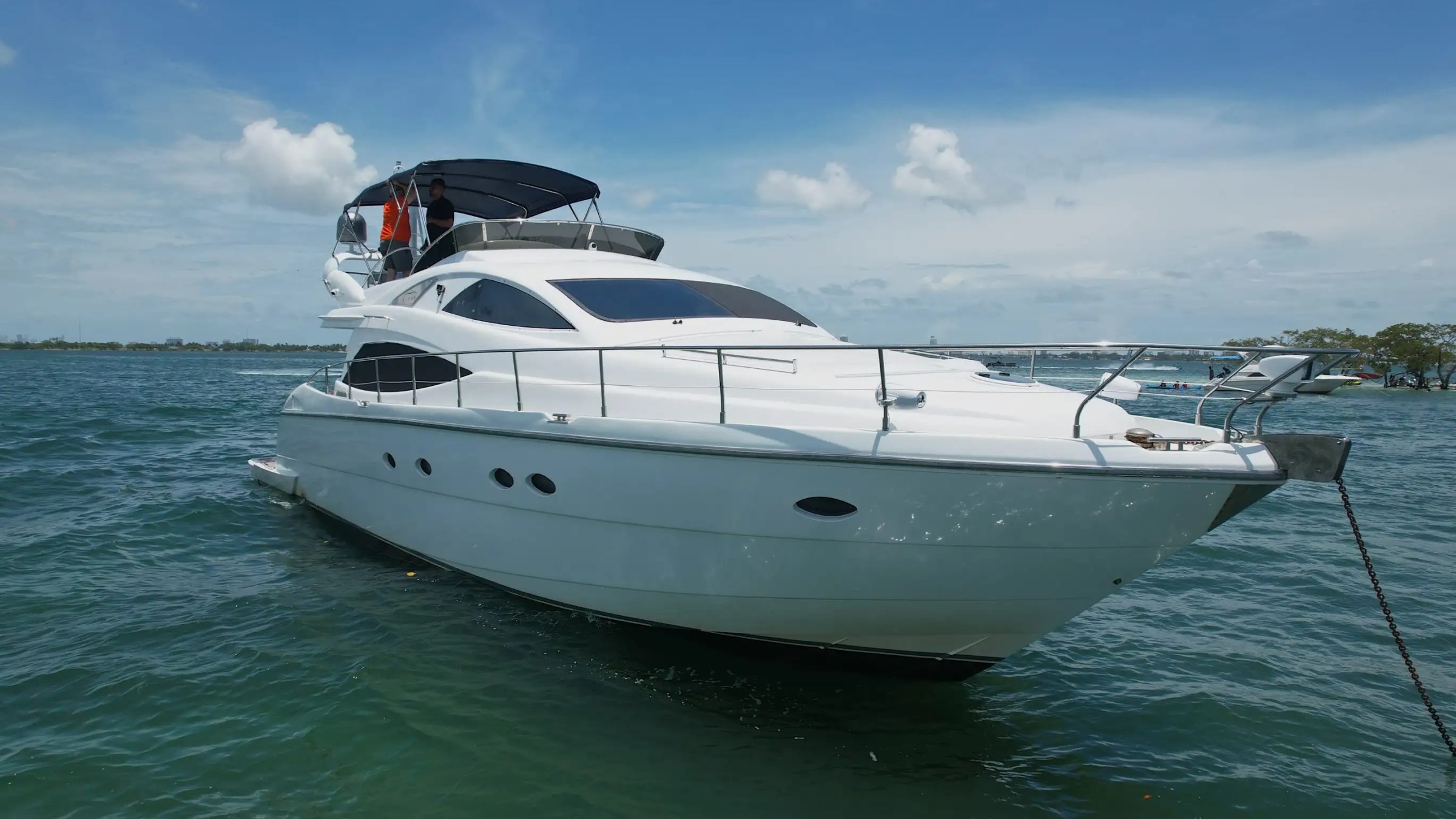 Luxurious white yacht anchored on clear blue water under a sunny sky.
