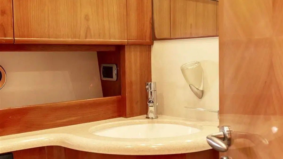 Small bathroom with wood cabinets, sink, and partial open door.