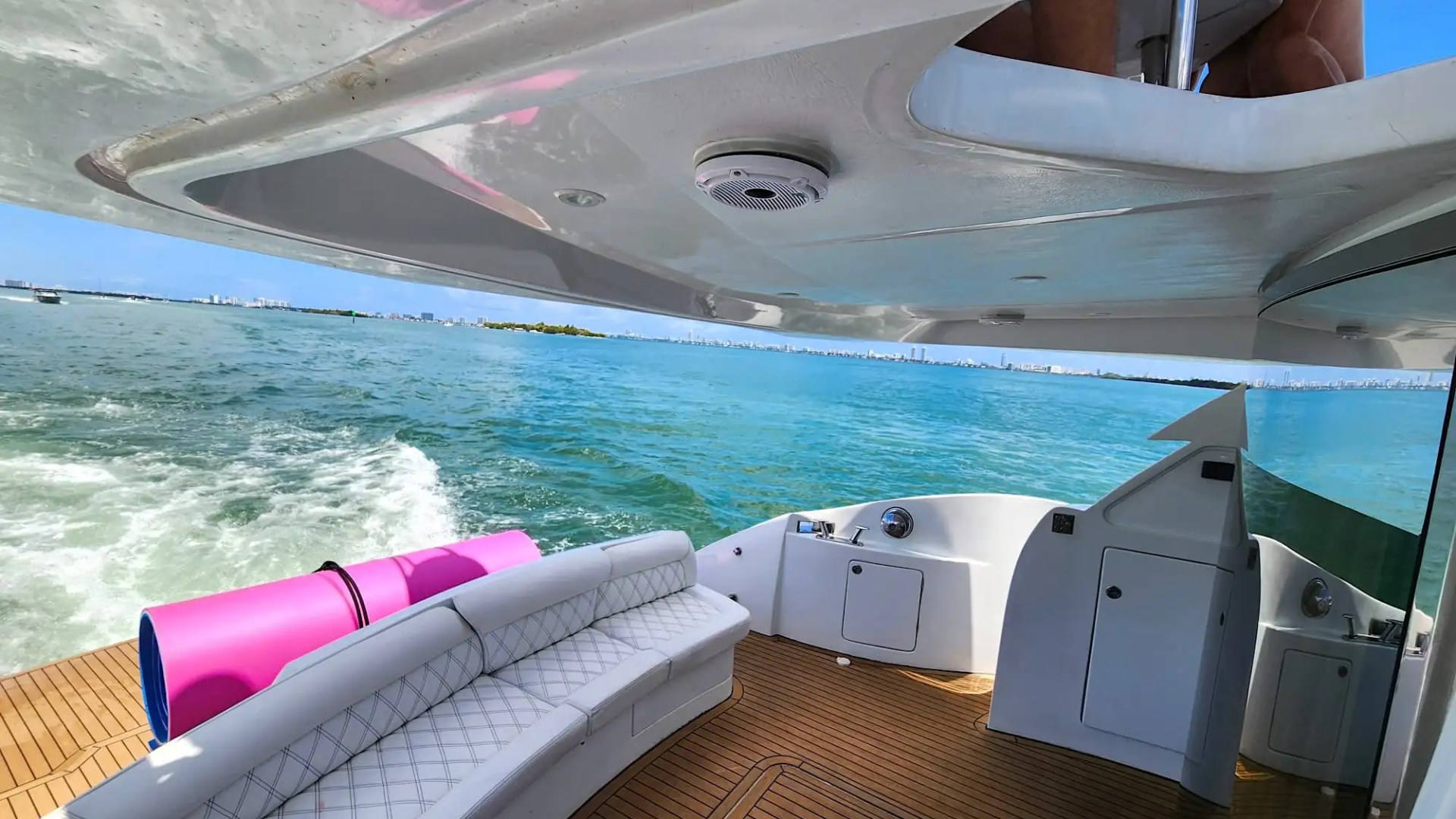 View from a boat's deck with seating, pink floats, and ocean in the background.