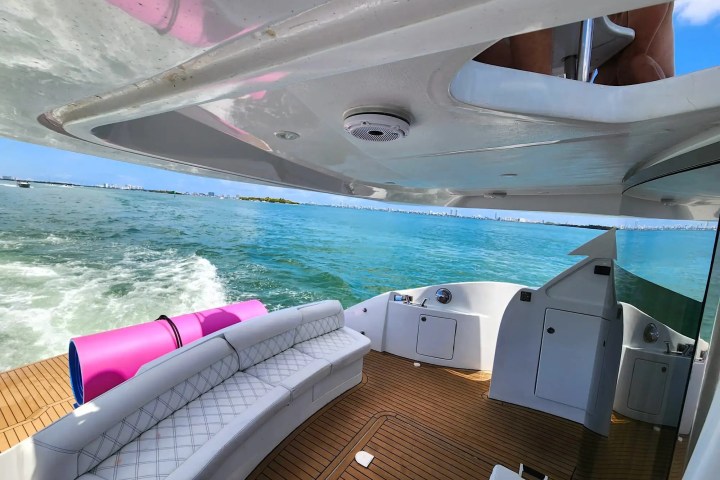 View from a boat's deck with seating, pink floats, and ocean in the background.