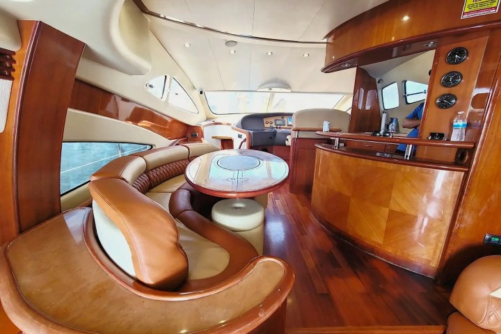 Luxurious yacht interior with curved leather seating, wooden tables, and bar area.