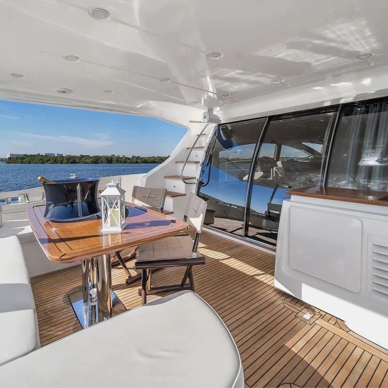 Luxury yacht deck with seating, wooden table, and lake view.