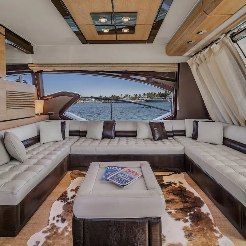 Luxurious yacht interior with cream and brown couches, nautical decor, and water view.