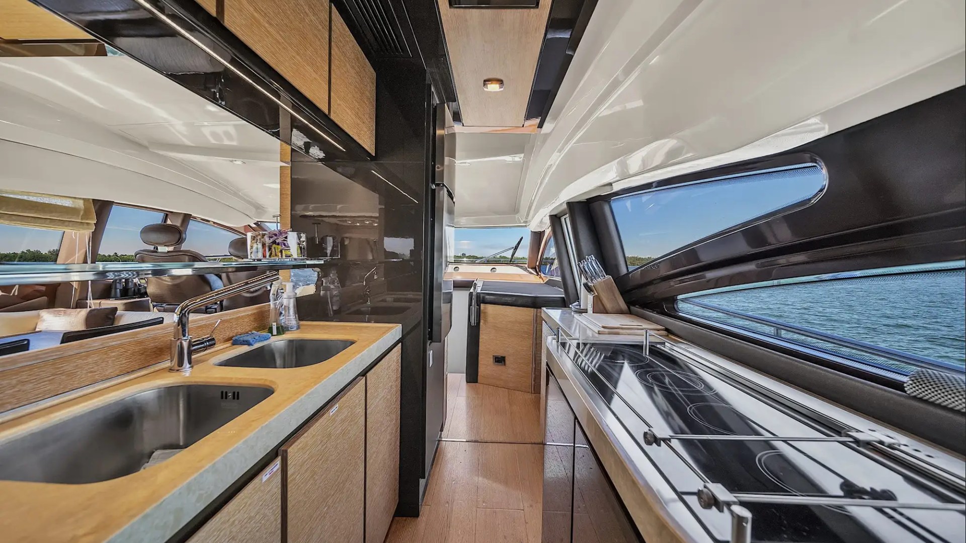 Luxurious yacht kitchen interior with sleek countertops, dual sinks, and modern stovetop.
