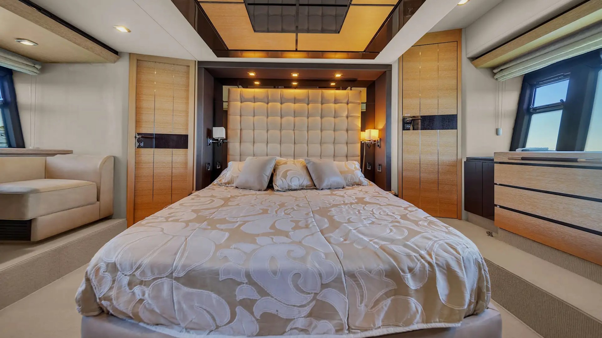 Luxurious bedroom with a large bed, tufted headboard, wood accents, and soft lighting.