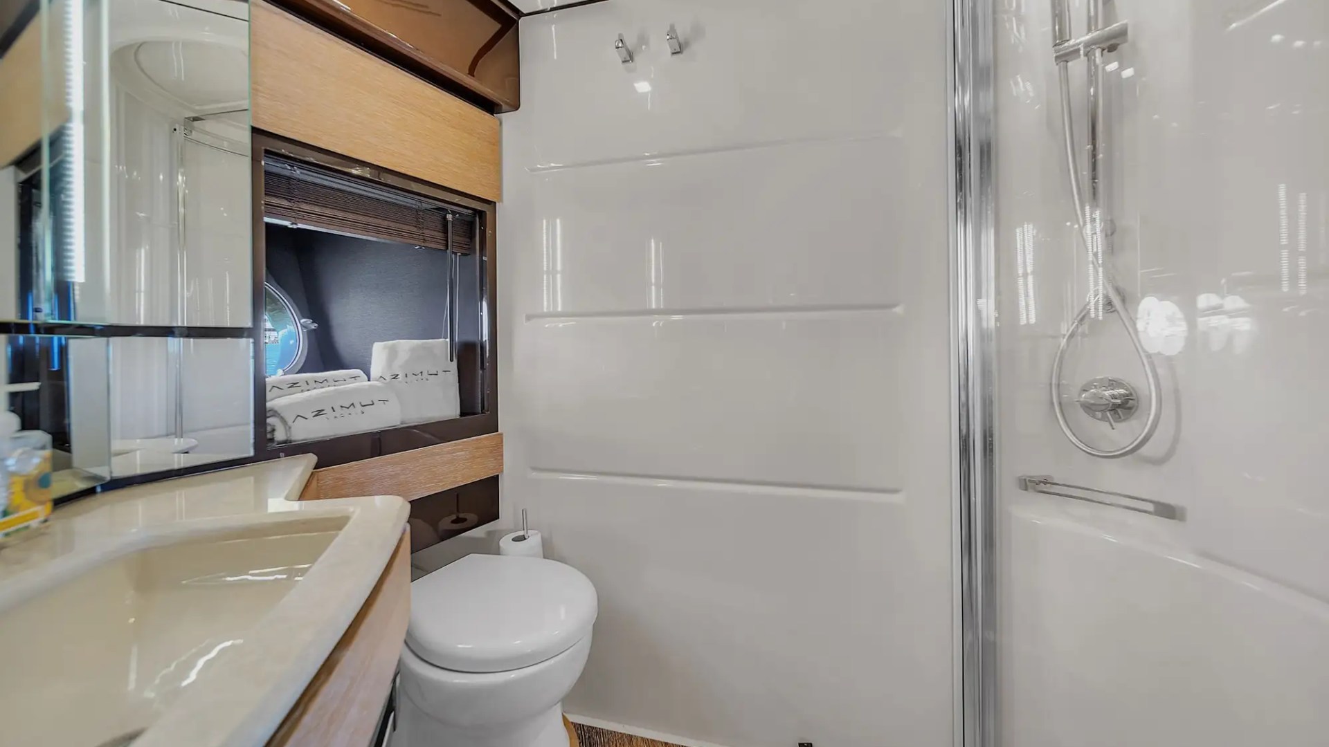 Compact bathroom with a toilet, sink, mirror, and shower in a modern design.