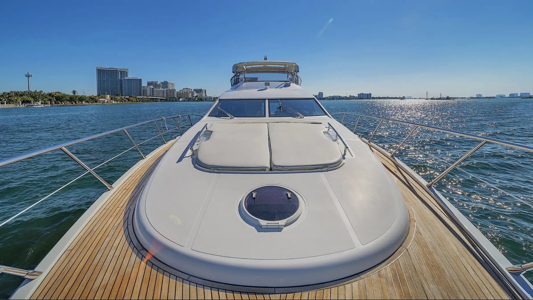 View from yacht deck with city skyline and calm ocean under clear blue sky.