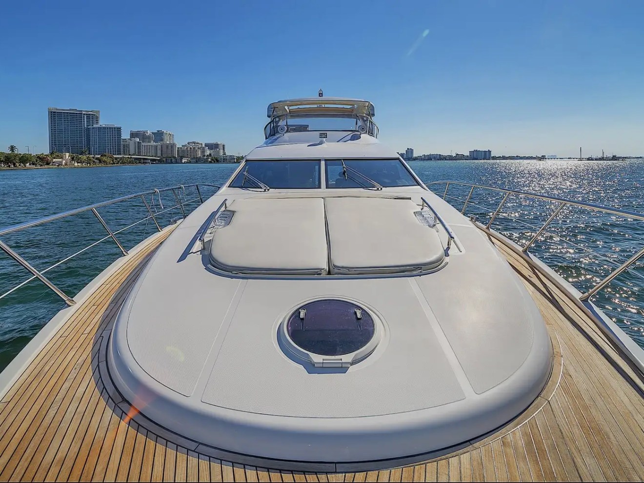 View from yacht deck with city skyline and calm ocean under clear blue sky.