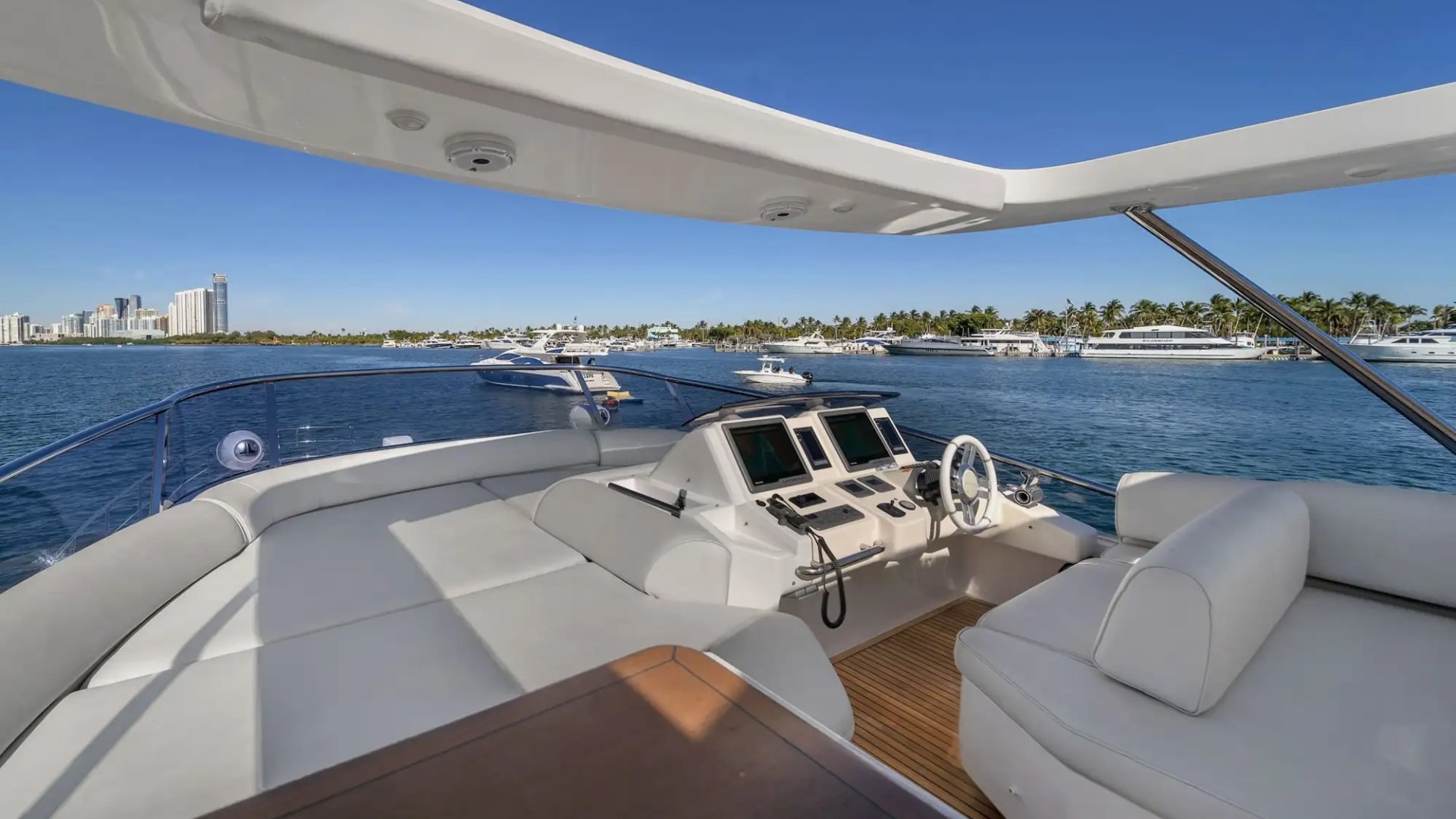 Luxurious boat deck with seating overlooking calm water and a city skyline.