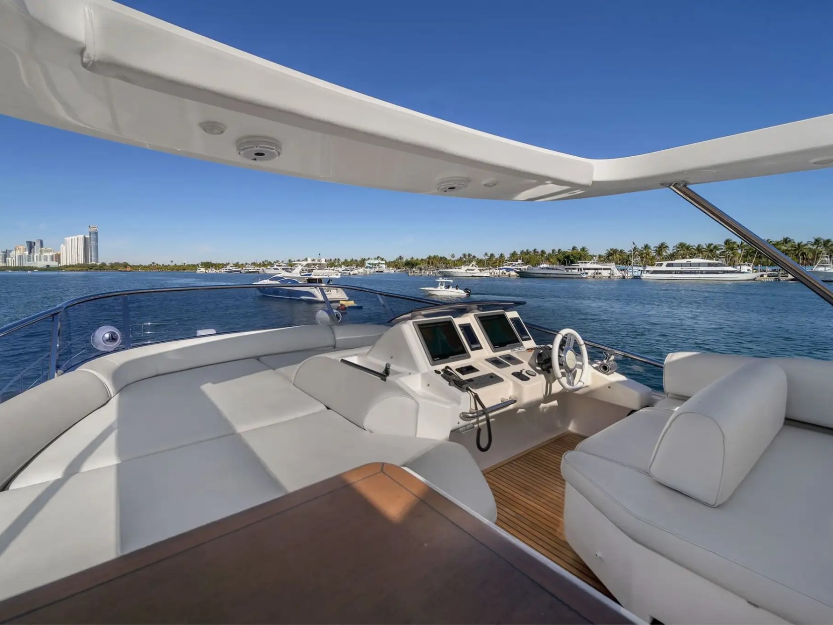 Luxurious boat deck with seating overlooking calm water and a city skyline.