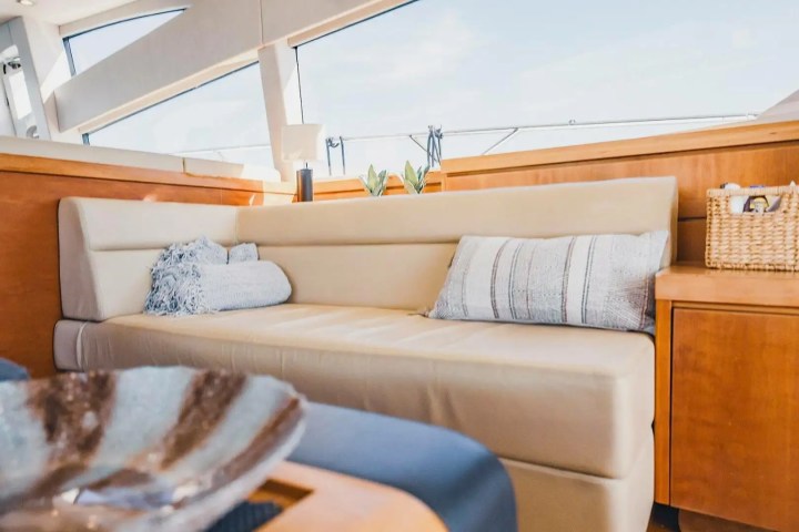 Beige couch with pillows in a cozy boat interior, wooden accents, and basket with items.