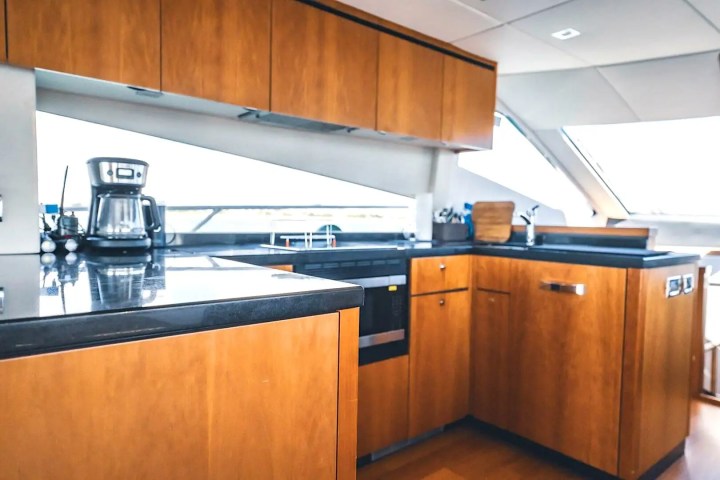 Modern kitchen with wood cabinets, black countertops, and a large window.
