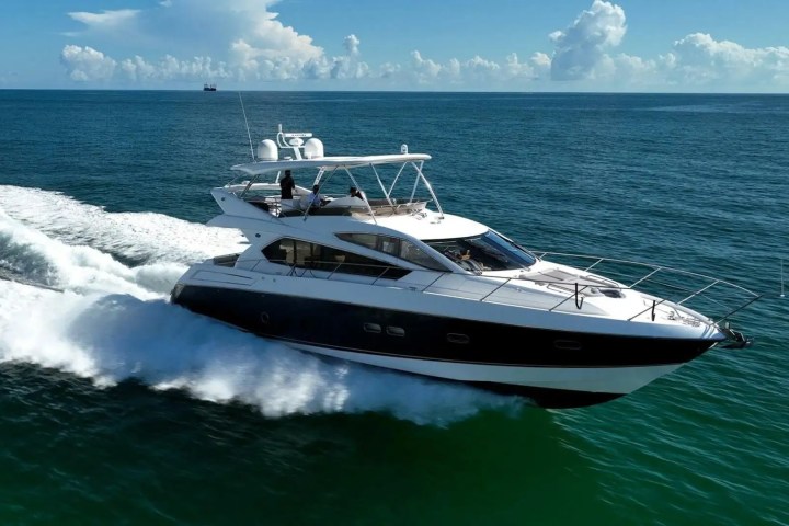 Luxury yacht cruising on the open sea with a blue sky and clouds in the background.