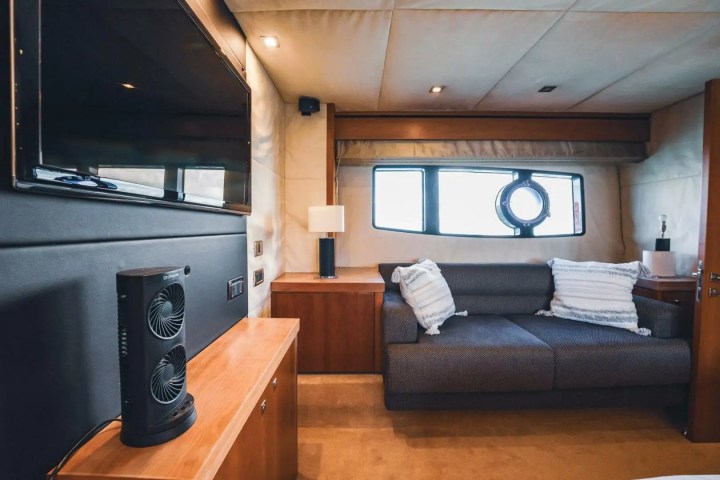 Cozy yacht interior with sofa, pillows, TV, and window view.