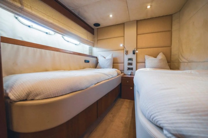 Luxury yacht cabin with two beds, beige walls, and ambient lighting.