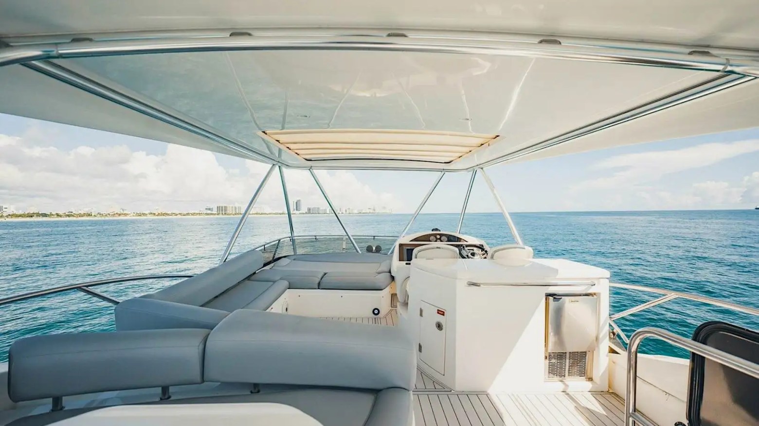 View from yacht deck with seating area overlooking calm ocean and distant coastline.
