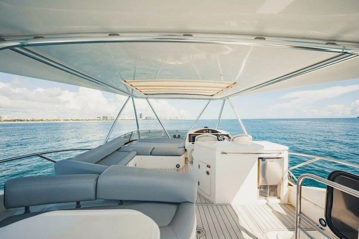 View from yacht deck with seating area overlooking calm ocean and distant coastline.