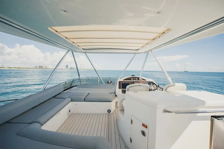 White boat interior with seating on open water under a clear sky.