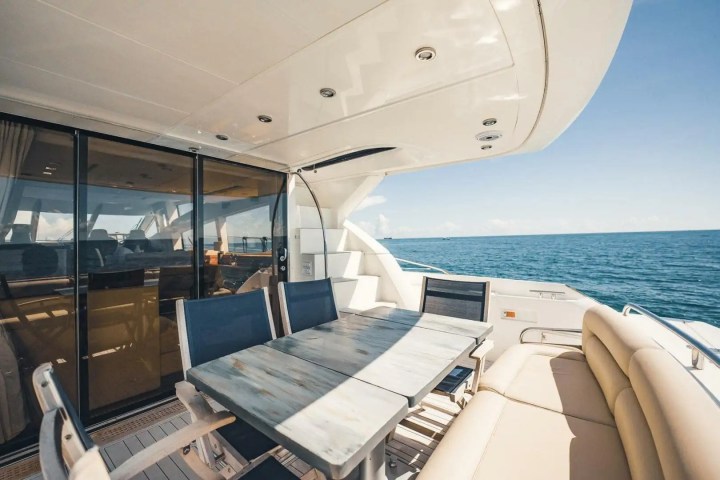 Deck of a luxury yacht with a table, chairs, and view of the ocean.