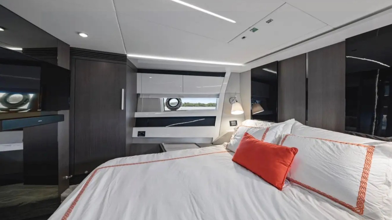 Luxurious yacht bedroom with modern decor, white bedding, and red accent pillow.