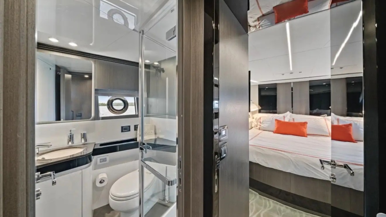 Bathroom and bedroom with orange pillows on a yacht.