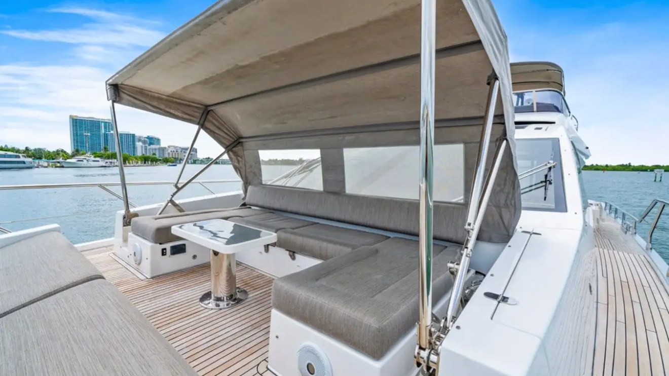 Luxury yacht deck with gray seating, table, and canopy, view of city skyline.