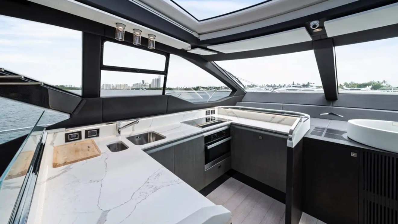 Modern yacht kitchen with marble countertops and stainless appliances, large windows overlooking water view.