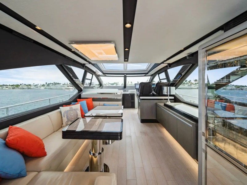 Luxurious yacht interior with beige sofa, colorful cushions, wood floor, and large windows overlooking the sea.